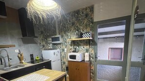 Una cocina compacta con una isla central, microondas, refrigerador y un mueble de madera.