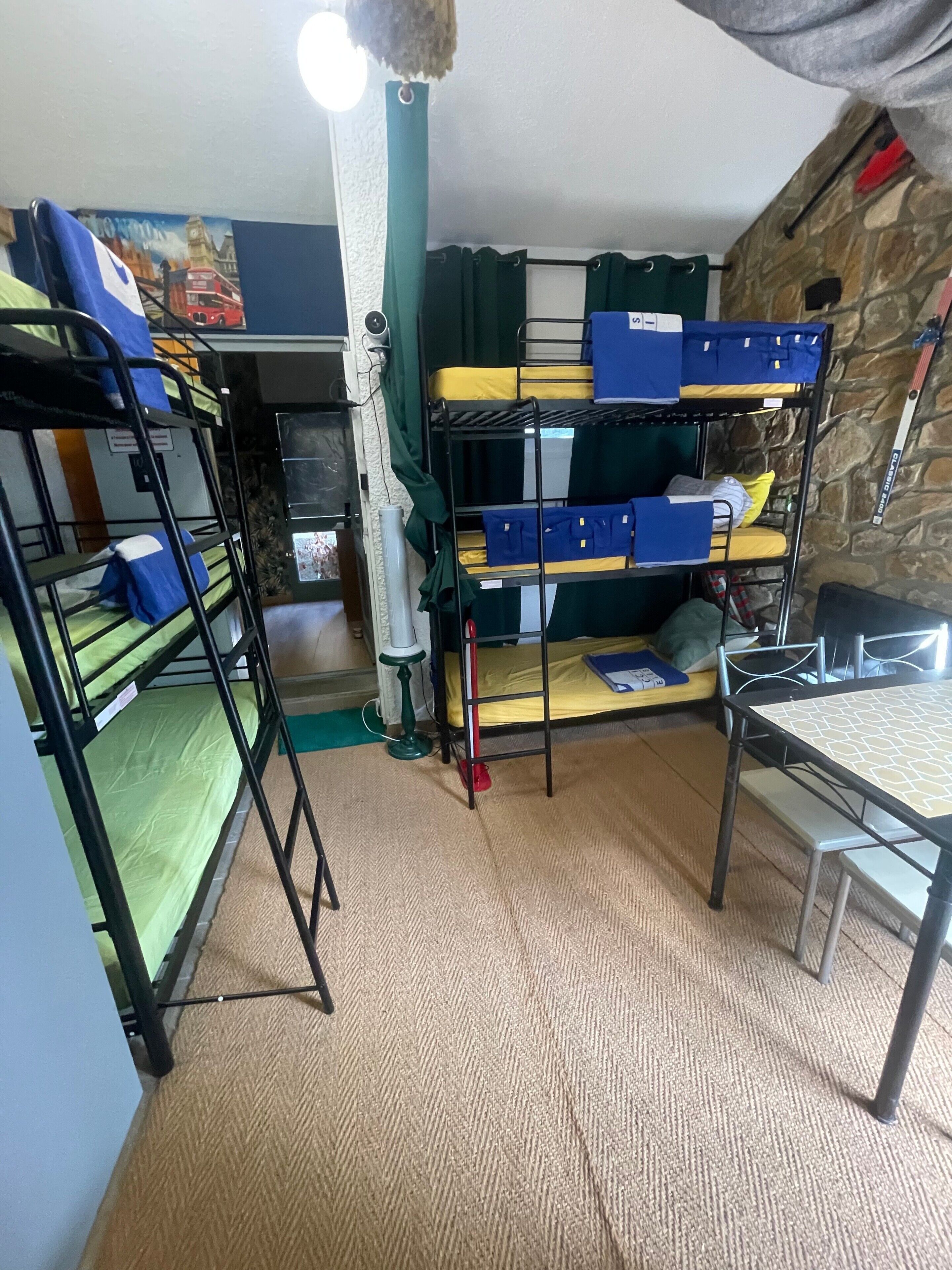 Dormitorio con literas, una mesa y pared de piedra.