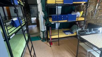 Dormitorio con literas, una mesa y pared de piedra.