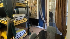 Dormitorio con literas, un escritorio, una escalera y una pared de piedra.