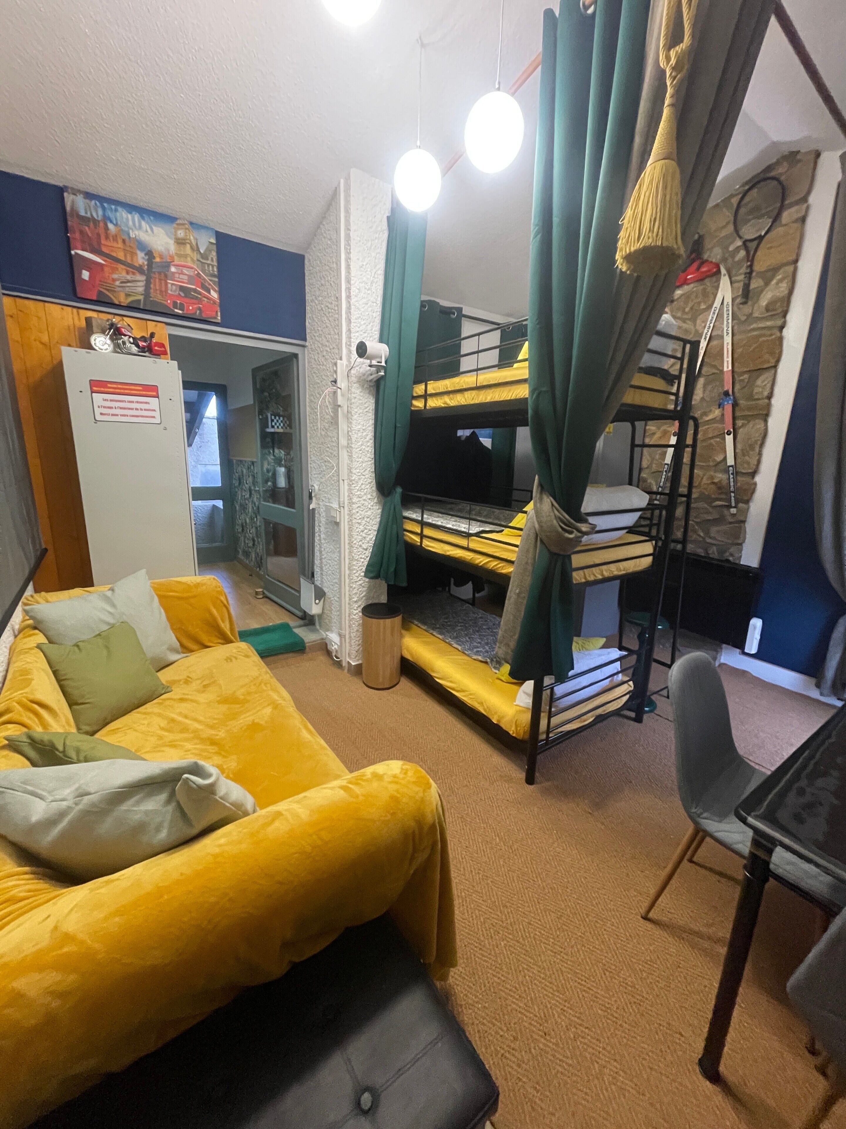 A room with a bunk bed, a yellow sofa, a desk, and a chair.