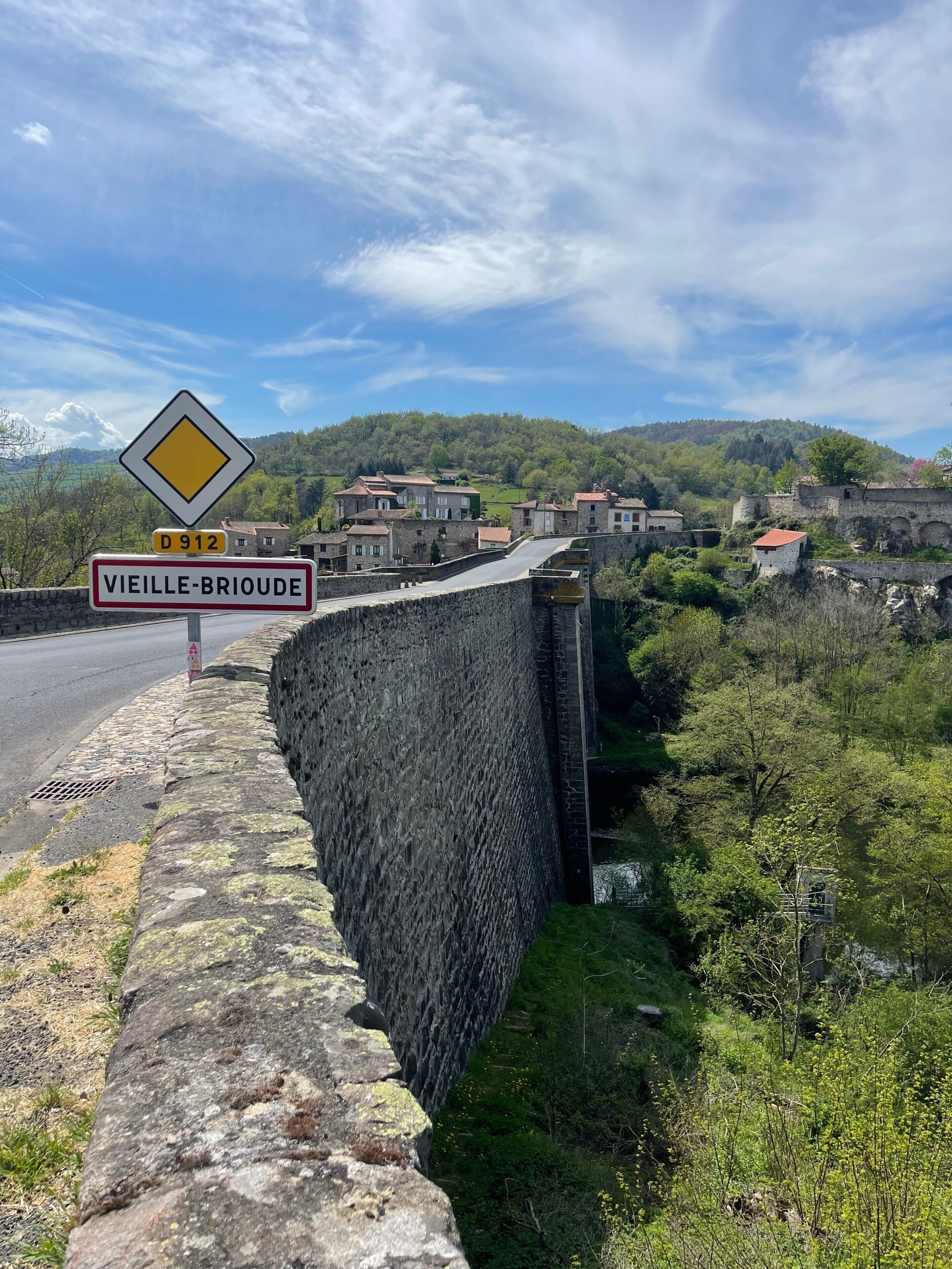 Un muro de piedra, una señal de tráfico y un pueblo con edificios tradicionales.