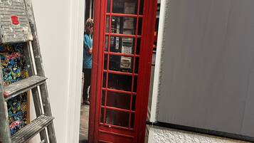 A red telephone booth with a sign reading 'TELEPHONE' and a WC sign above it.