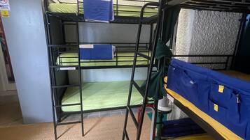 Habitación con literas, un dardo en la pared, un refrigerador pequeño y dispensador de agua.