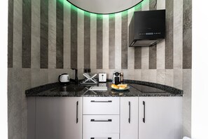 A modern kitchen with a granite countertop, white cabinets, a black range hood, and a striped wall. - Coxy Apartment in Almaria Near Centre (Torremolinos)