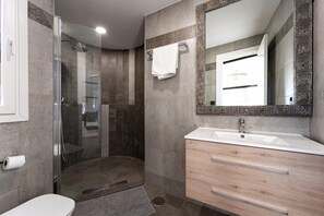 A modern bathroom with a glass shower enclosure, a white sink, and a wooden vanity. - Coxy Apartment in Almaria Near Centre (Torremolinos)