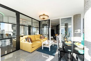 A modern living room with a yellow sofa, a white coffee table, and a dining area with a black table and chairs. - Coxy Apartment in Almaria Near Centre (Torremolinos)