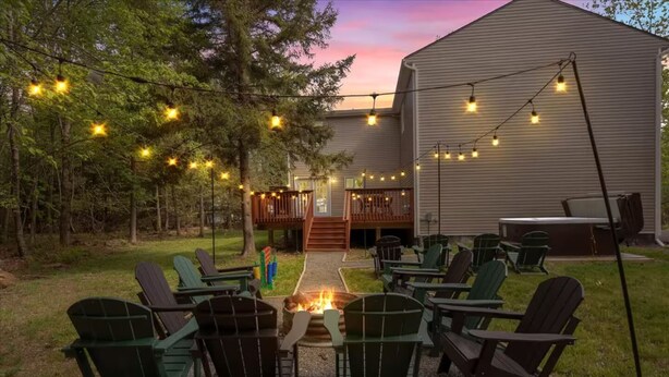 Un espace extérieur aménagé avec des chaises Adirondack, un foyer et des guirlandes lumineuses.