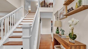 Un escalier avec des rampes blanches et des marches en bois menant à un deuxième étage.