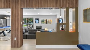 A modern living room with a pool table, a sofa, and a fireplace.