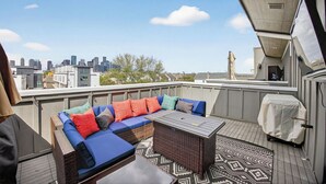 A rooftop patio with a blue sofa, a small table, and a patterned rug. - Urban EaDo Retreat - 3BR Townhome w/ Deck (Houston)