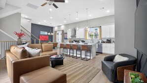 A modern kitchen with white cabinets, a central island, and pendant lighting. - Urban EaDo Retreat - 3BR Townhome w/ Deck (Houston)