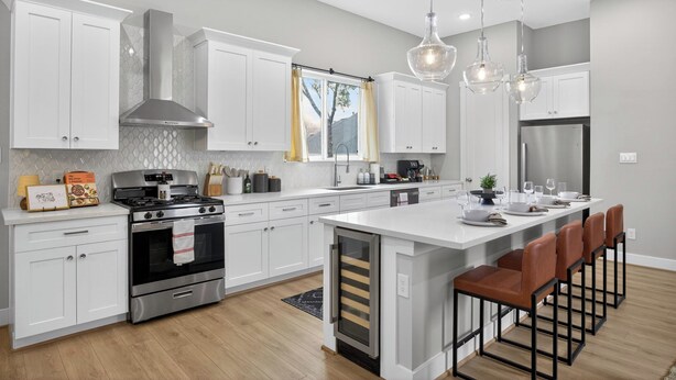 A modern kitchen with white cabinets, stainless steel appliances, and a central island with bar stools. - Urban EaDo Retreat - 3BR Townhome w/ Deck (Houston)