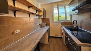 Une cuisine moderne avec des meubles en bois, un four encastré, un évier et une fenêtre donnant sur un paysage verdoyant.
