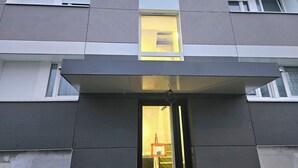 Une façade de bâtiment moderne, dotée de grandes fenêtres, d’un toit plat et d’une entrée centrale.