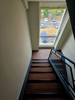 A staircase with a metal handrail leading to a door with a view of a parking lot. - Beautiful apartment for families or groups with free parking   (Mérignac)