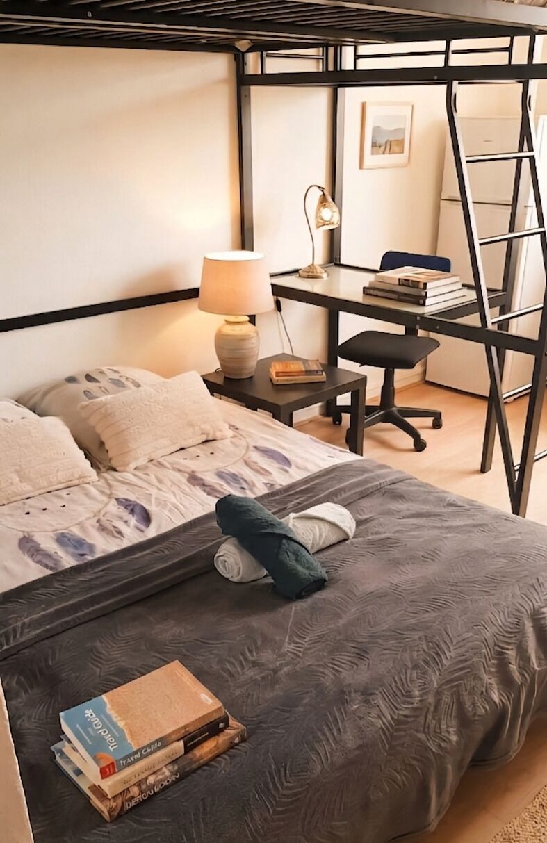 Une chambre à coucher avec un lit, un bureau, une chaise et une échelle.