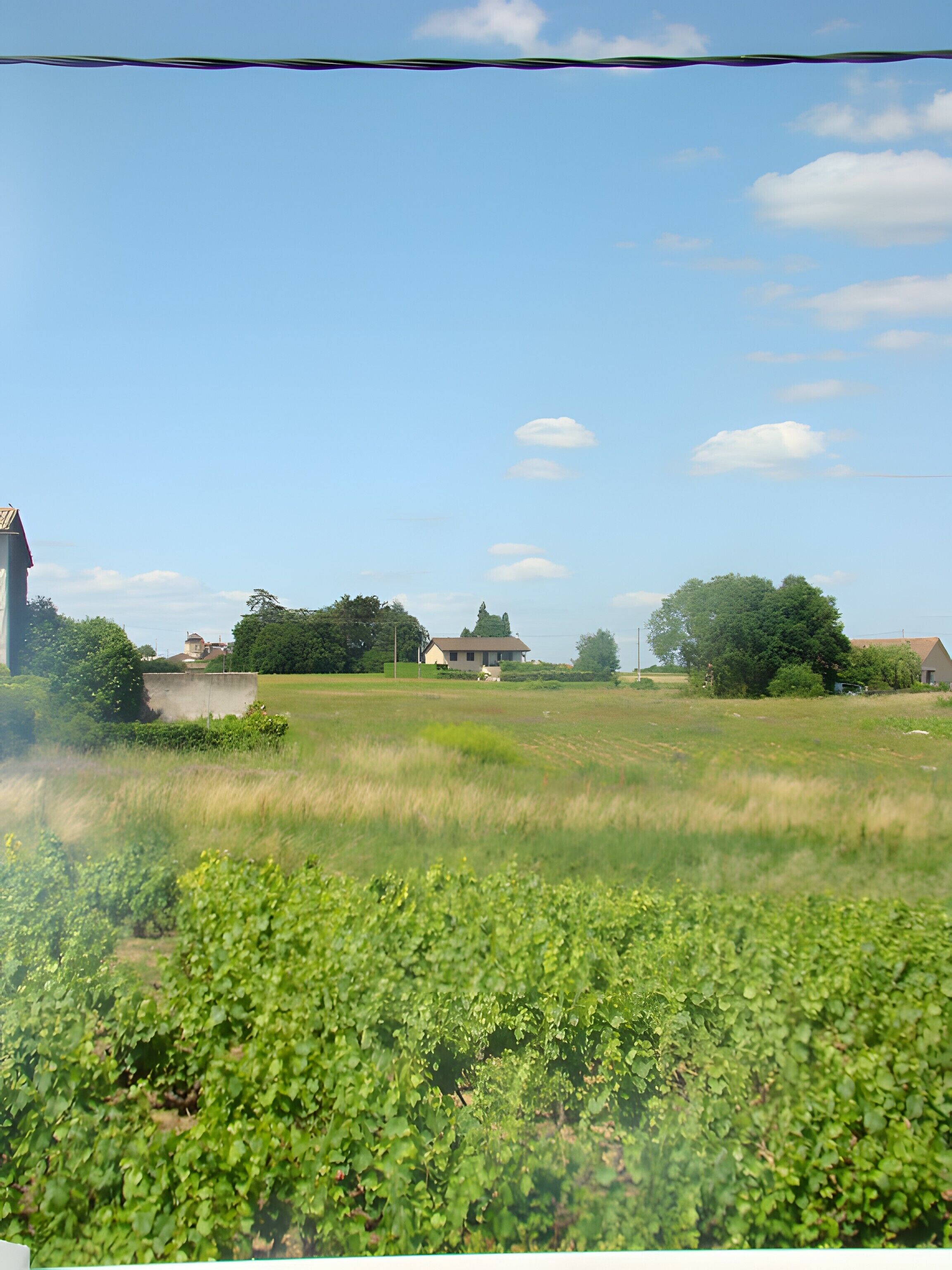 Paisagem rural com um campo, uma casa e uma igreja.