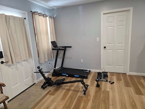 Ein Heimfitnessraum mit Laufband, Ergometer und Gewichten.