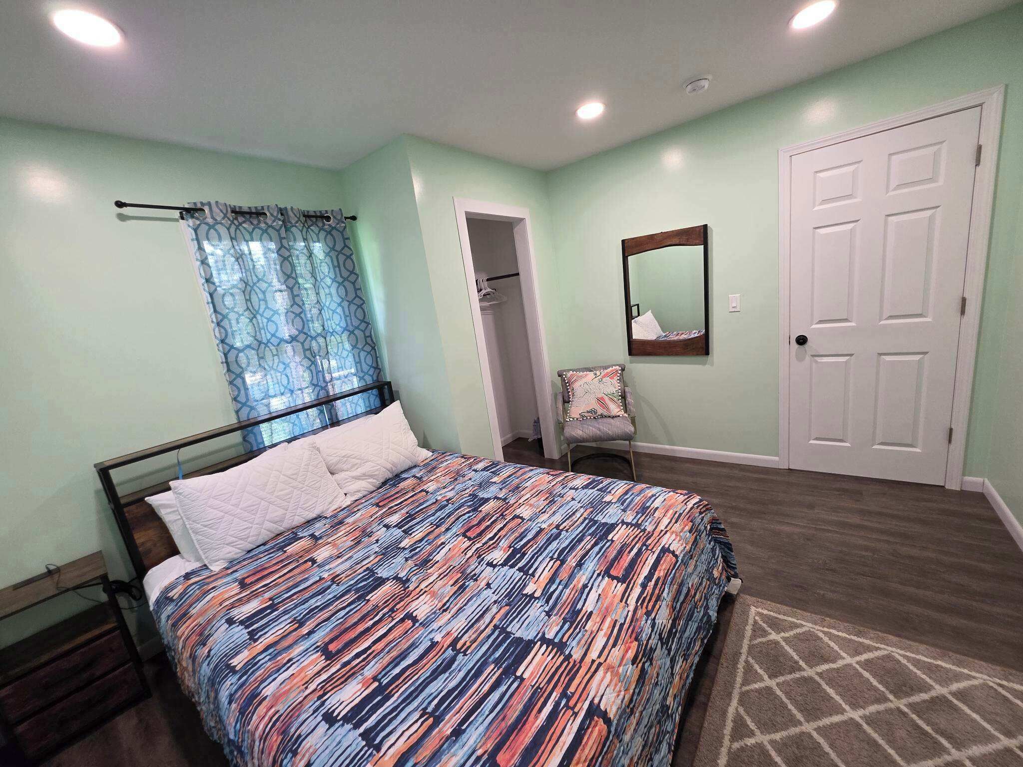 Une chambre à coucher avec un lit, une porte, un miroir et une armoire.