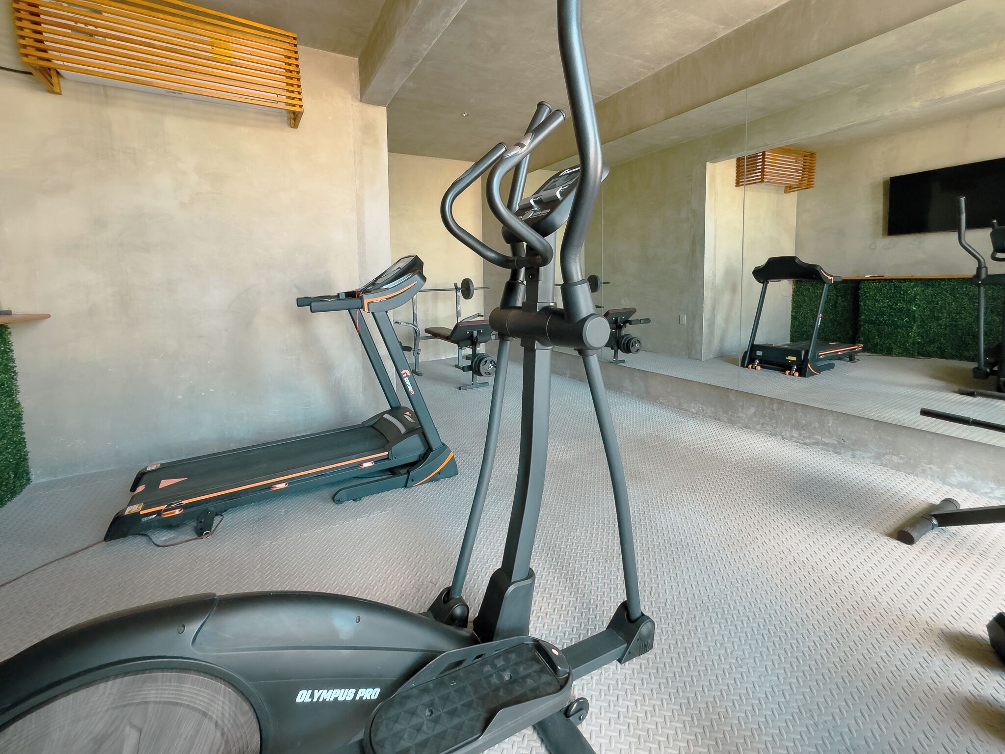 Een sportschool met loopbanden, een elliptische trainer en een hometrainer.
