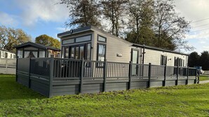 A modern mobile home with a fenced deck, large windows, and a 'WILLYN' sign. - Host & Stay | The White Swan (Allerthorpe)