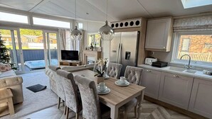 A modern kitchen with a built-in oven, a dining area with a herringbone floor pattern, and a large window providing natural light. - Host & Stay | The White Swan (Allerthorpe)