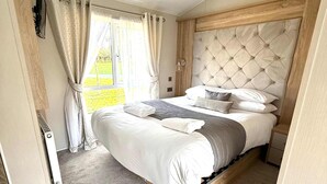 A bedroom with a large bed, a window with curtains, a radiator, and a wooden headboard. - Host & Stay | The White Swan (Allerthorpe)