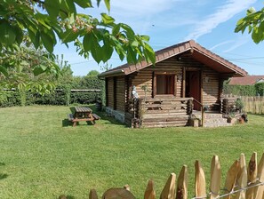A log cabin with a porch, a picnic table, and a fenced yard. - Ideal Chalet for Hiking (Valorbiquet)