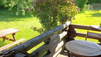 Een houten terras met picknicktafels en een ronde tafel.