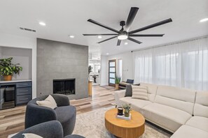 A modern living room with a fireplace, a ceiling fan, and a sofa. - Your Modern Scandinavian Escape/King Beds/Spa-Like Master Shower/Prime Dallas (Dallas)