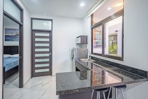 A compact kitchen with a built-in stove, a sink, and a window with a view of a street. - 17BR Jacó Retreat w/ Private Pool for Groups (Jaco)