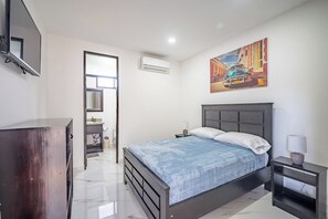 A bedroom with a bed, bedside table, and a painting on the wall. - 17BR Jacó Retreat w/ Private Pool for Groups (Jaco)
