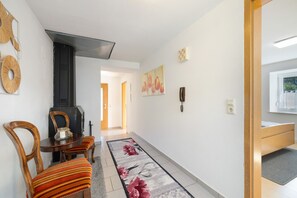 Un pasillo con una mesa de comedor de madera, sillas, un tapete y un teléfono fijo en la pared.
