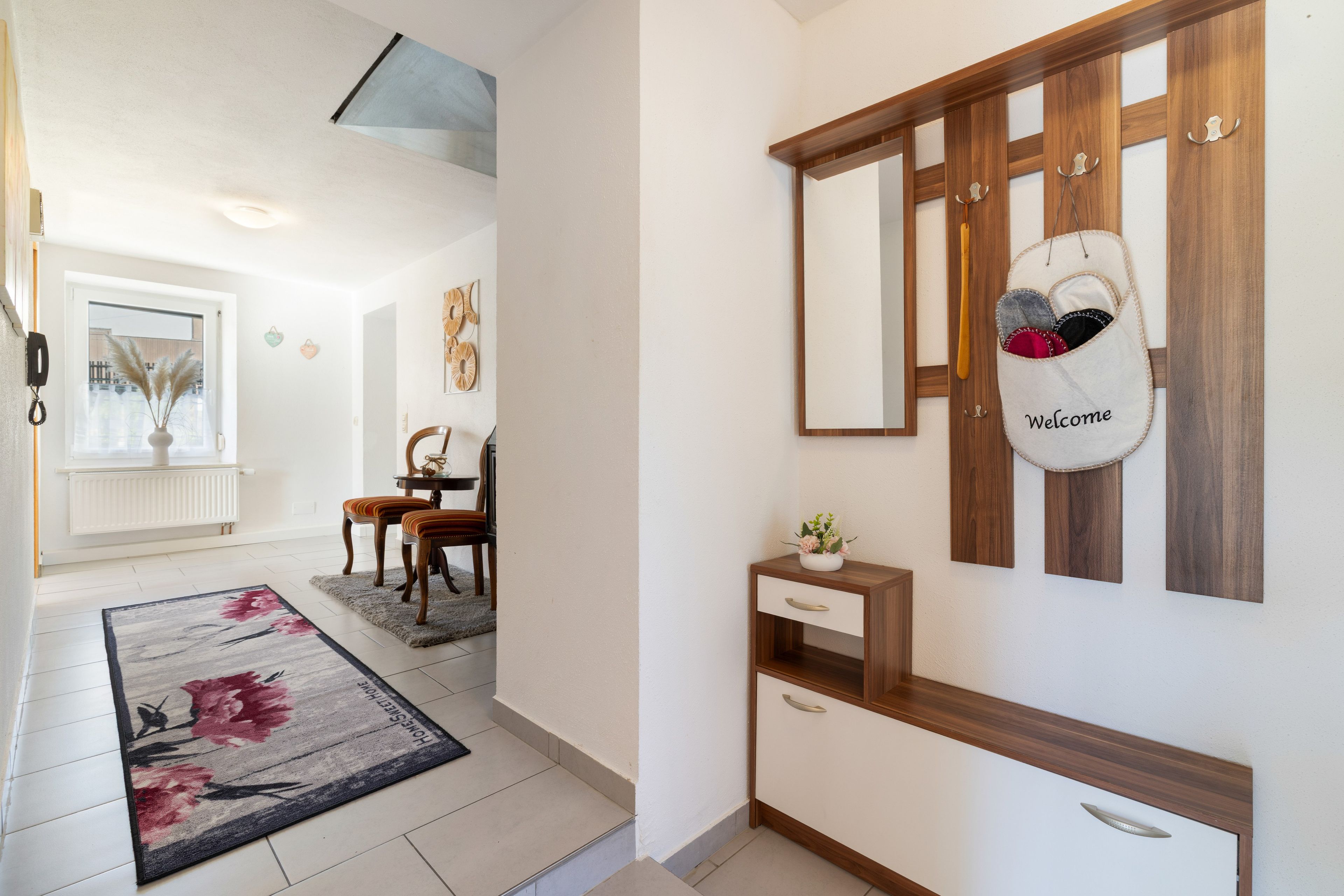 Un couloir avec un banc en bois, une petite table et un sac d’accueil accroché au mur.