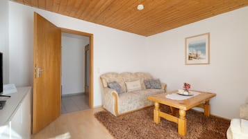 Une pièce avec un plafond en bois, un canapé, une table avec un set de table et un tableau encadré au mur.