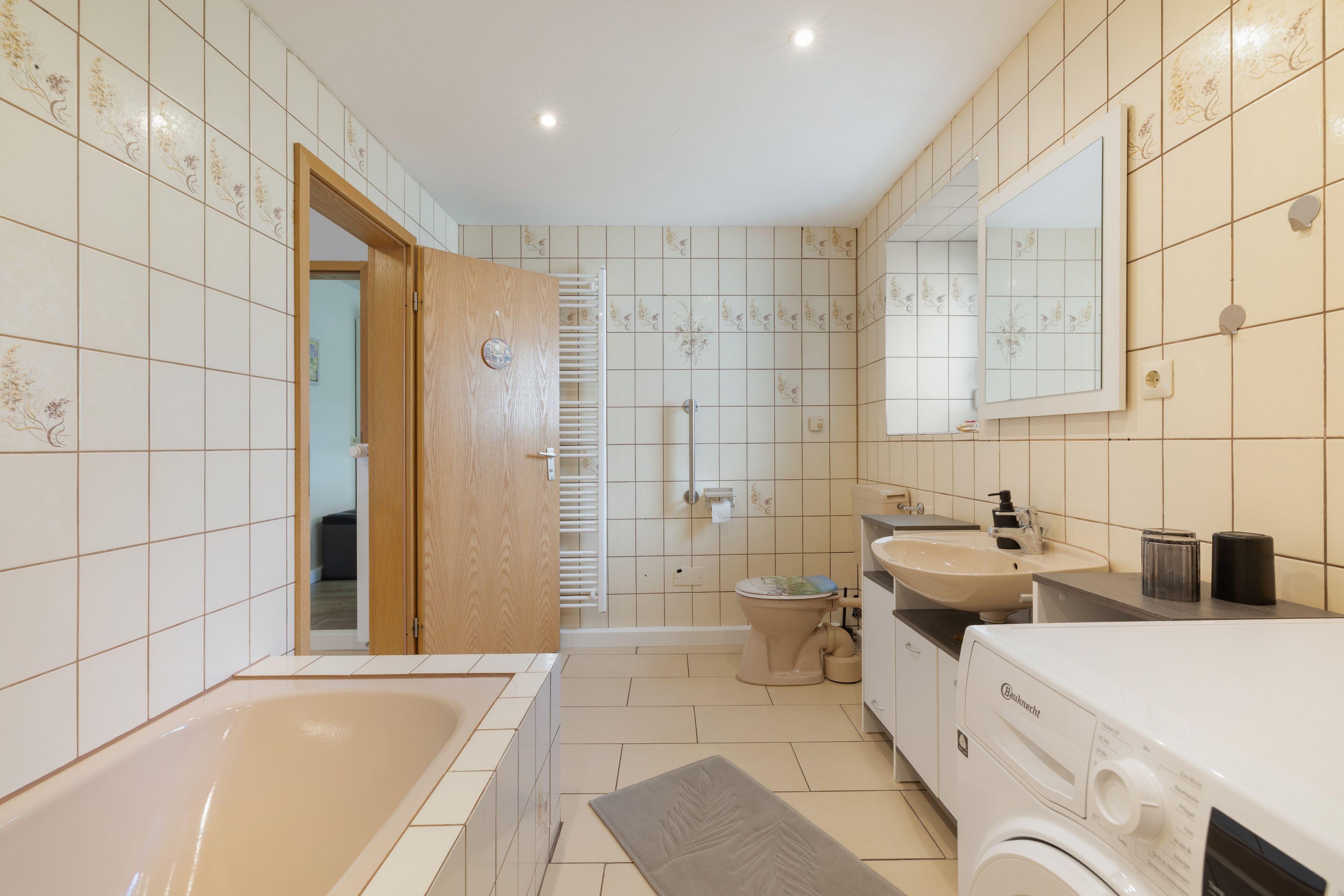 Ein modernes Badezimmer mit Badewanne, Toilette, Waschbecken und Spiegel.
