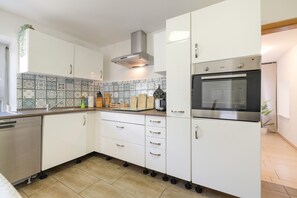 Una cocina moderna con armarios blancos, horno de acero inoxidable y lavavajillas.