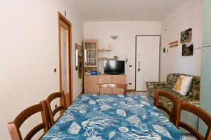 Un espace repas comprenant une table, des chaises, un téléviseur, un meuble et un canapé.