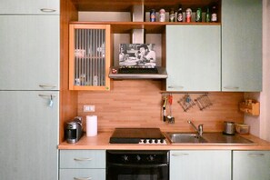 Una cucina compatta con piano cottura, lavello e pensili.