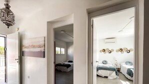 Une chambre d’hôtel comprenant un lit, des tables de chevet, une horloge murale et une porte donnant sur une autre pièce.