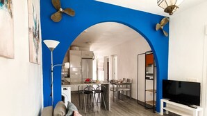 Un salon comprenant un canapé, un téléviseur et un coin repas avec des chaises et une table.