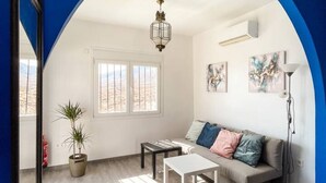 Un salon avec un canapé, deux tables basses, une plante en pot et des œuvres d’art accrochées au mur.