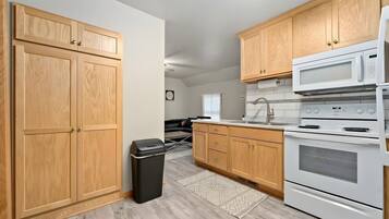 A kitchen with wooden cabinets, a white microwave, and a stove.