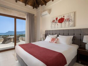 Een slaapkamer met een groot bed, uitzicht op zee en een schilderij aan de muur.