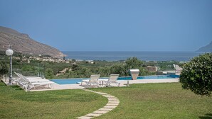 A pool area with lounge chairs, a pathway, and a view of the sea and distant landscape. - Elegant Chania Villa for 4 Guests (Kissamos)