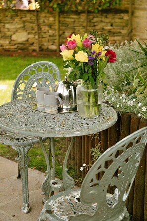 Et metalbord med en kande, kopper og et fad med blomster.