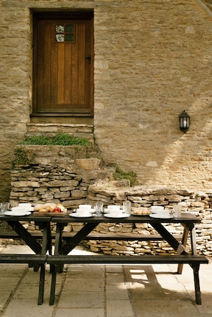 A stone building with a wooden door and a stone wall. - Dunford Barn (Lechlade)