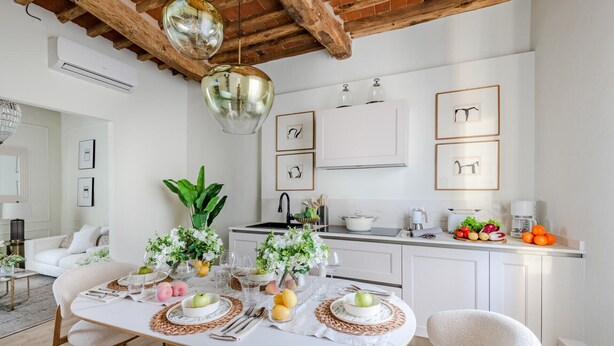 A modern kitchen with white cabinetry, a central island with a dining setup, and a rustic ceiling.