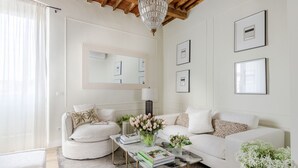 A modern living room with a white sofa, a coffee table, and a chandelier.